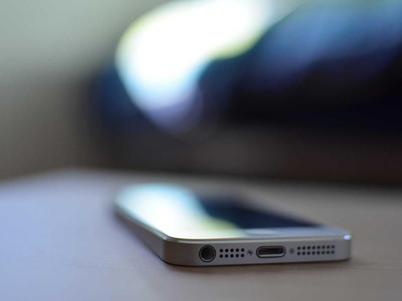 Smartphone lying on a surface with focus on its bottom edge showing the headphone jack and charging port.